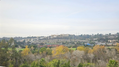 Trolley rolling through Mission Valley with USD on the hill behind
